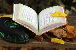 Quran Prints: An open Holy Quran on wood stand and a kufi, France, Europe