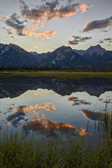 Rocky Mountains Prints: Orange clouds at sunset reflected in a lake