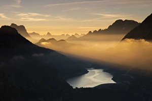 Orange light beam and mist on peaks of Dolomiti and Fedaia Pass, Cima Belvedere, Val di Fassa
