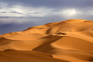 Erg Chebbi Prints: Orange sand dunes against stormy sky