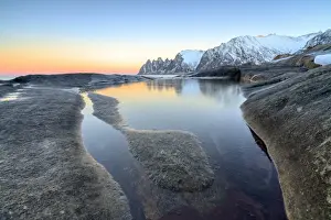 Tungeneset Prints: Orange sky at sunset reflected on snowy peaks and the frozen sea surrounded by rocks Tungeneset