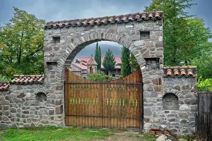 Fence Prints: Orthodox Ikoti Monastery entrance showing stone architecture and wooden gates in Leningor region