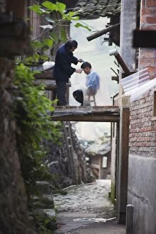 An outdoor barber cutting a boys hair in Langde village, Guizhou Province