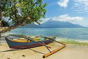Canoe Prints: Outrigger canoe moored on Kalea Beach with active Karangetang volcano beyond