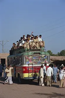 Public Transport Prints: Overloaded bus with men riding on the roof near Multan in Pakistan