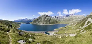 Grassy Prints: Panorama of the blue Lake Montespluga surrounded by rocky peaks in summer
