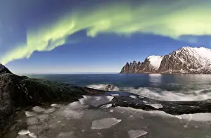 Swirling Prints: Panorama of frozen sea and rocky peaks illuminated by the Northern Lights (aurora borealis)