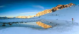 Photographer Prints: Panorama of Lake, Piz Umbrail at dawn with photographer in action framed by snow