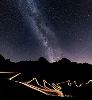 Silhouetted Gallery: Panorama of the Milky Way and lights of car trace at Stelvio Pass, Valtellina, Lombardy