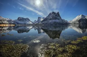 Panorama of snowy peaks reflected in sea in a cold starry night, Bergsbotn, Senja