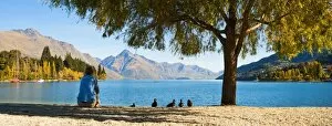 Images Dated 8th April 2011: Panorama of a tourist relaxing by Lake Wakatipu in autumn at Queenstown, Otago, South Island