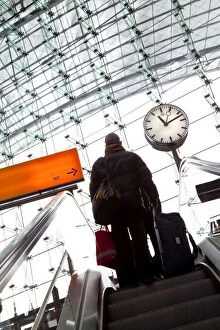 Passenger on escalator and platform clock at modern train station, Berlin