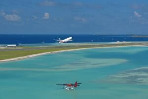 Passenger jet taking off from Male International Airport, and Maldivian air taxi ready to take off