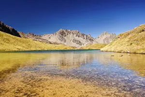Reservoir Prints: Peaceful wilderness lake beneath sunlit mountain range in natural reserve