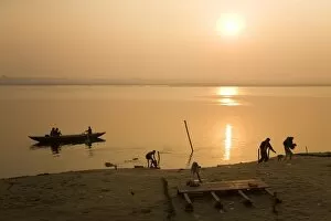 People go about their daily business as the sun rises over the Ganga (Ganges) River at Varanasi