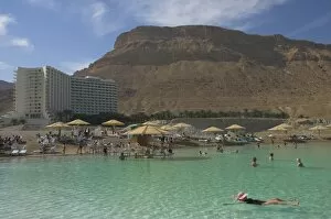 People floating in the sea and Hyatt hotel and desert