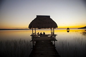 Thatched Roof Prints: People relaxing at sunset, Lago Peten Itza, El Remate, Guatemala, Central America