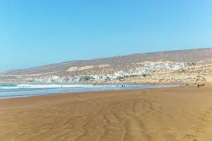 Essaouira Prints: People walking along sandy beach at low tide near village of Taghazout