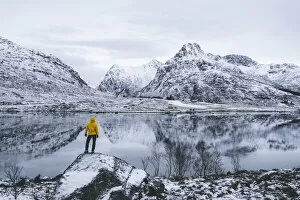 Nordland Gallery: Person admiring the snowcapped mountains reflected in frozen sea, Flakstadpollen, Flakstadoya