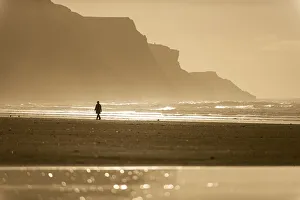 Swansea Prints: Person walking along beach in the evening sunlight, Rhossili, Gower Peninsula, Swansea