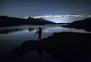Photographer Prints: Photographer admires reflection on Rossett Lake at night, Gran Paradiso National Park