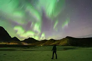 40 44 Years Prints: Photographer contemplating the Aurora Borealis (Northern Lights) in the starry sky from Haukland beach