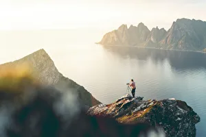35 39 Years Gallery: Photographer with tripod on Husfjellet mountain watching sunset on sharp peaks of mount