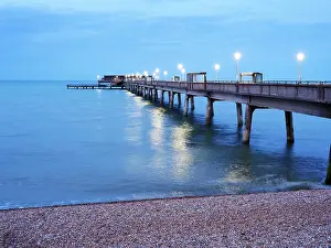 Walkway Prints: Pier extends into the sea at dusk with lights illuminating the walkway in Deal Kent