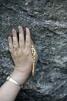 Touching Prints: Pilgrim touching the Lourdes grotto, Lourdes, Hautes Pyrenees, France, Europe