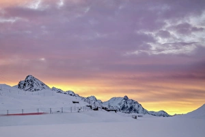Pink clouds and snow frame the Bernina Express train at dawn, Bernina Pass, Canton of Graubunden