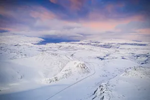Arctic Gallery: Pink sky at sunrise over Tanafjordveien road crossing the snow capped mountains, Tana