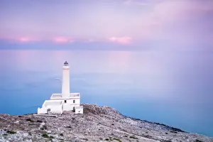 Pink sky on turquoise sea frames the lighthouse at Punta Palascia at sunset, Otranto