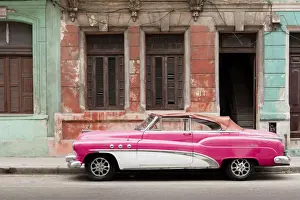 Shutters Prints: A pink and white vintage American convertible car parked on a street in Havana, Cuba