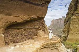 Turban Prints: Priest holding the hand cross on rocks outside Abuna Yemata Guh church