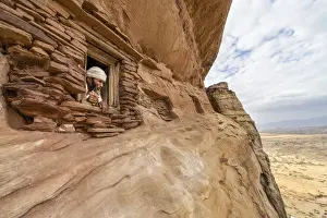 Males Prints: Priest looking out from a small window carved into rocks in Abuna Yemata Guh church