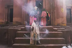 Priest swings an incense burner at the rock-hewn monolithic church of Bet Giyorgis (St