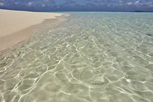Shallow Prints: Pristine shallow waters lap against the white coral sand of a tropical beach; Havodda Island