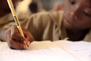Concentration Prints: Pupil taking notes in French class in African primary school, Lome, Togo, West Africa