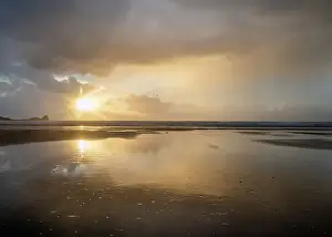 Reflective Prints: Rain clouds and reflections on Rhossili beach at sunset showing the shipwreck of the Helvetia
