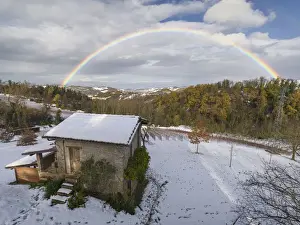 Rainbow arch above a small cottage and a snowy winter countryside landscape, Emilia Romagna, Italy, Europe