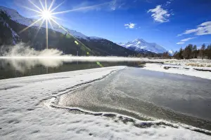 Maloja Prints: Rays of winter sun illuminate Lake Silvaplana still partially frozen, Maloja, Engadine