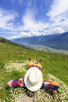 Contemplation Gallery: Rear view of man with hat lying on grass, Alpe Bassetta, Valtellina, Sondrio, Lombardy