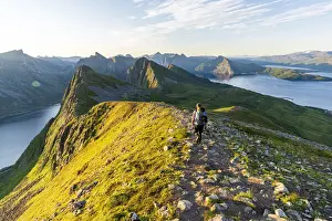 40 45 Years Prints: Rear view of man walking on path to Husfjellet mountain peak at sunrise, Senja island