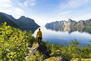 Photographer Prints: Rear view of photographer admiring the Mefjord blue water standing on rocks, Senja