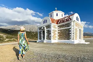 40 45 Years Prints: Rear view of woman in dress and straw hat walking to the Greek Orthodox church of Agia