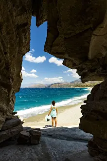 40 45 Years Prints: Rear view of young woman admiring the crystal sea from natural cave on Triopetra beach