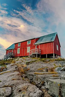 Cabin Prints: Red cabins on rocky terrain in Henningsvaer with cloudy sky in Lofoten Islands