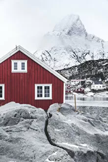 Nordland Gallery: Red Rorbu in the frozen landscape with snowcapped Olstind mountain in the background, Reine