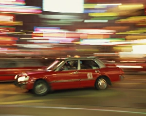 Taxi Prints: Red taxi driving at speed at night in Causeway Bay, Hong Kong, China, Asia