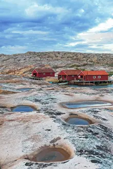 Gotaland Prints: Red traditional wooden cottages on granite rock in a cloudy day